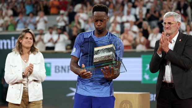 PARIS, FRANCE - MAY 25: Gael Monls of France is presented with a trophy containing Roland Garros clay and undersoil by Amelie Mauresmo - Tournament Director, and Gilles Moretton - President of the French Tennis Federation, following defeat against Hugo Gaston of France in their Men's Singles first round match on Day Two of the 2026 French Open at Roland Garros on May 25, 2026 in Paris, France. (Photo by Dan Istitene/Getty Images)