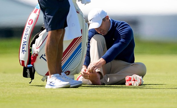 Rory McIlroy, of Northern Ireland, attends to his foot on the third fairway during a PGA Championship golf tournament practice round at Aronimink Golf Club, Tuesday, May 12, 2026, in Newtown Square, PA. (AP Photo/Matt Slocum)