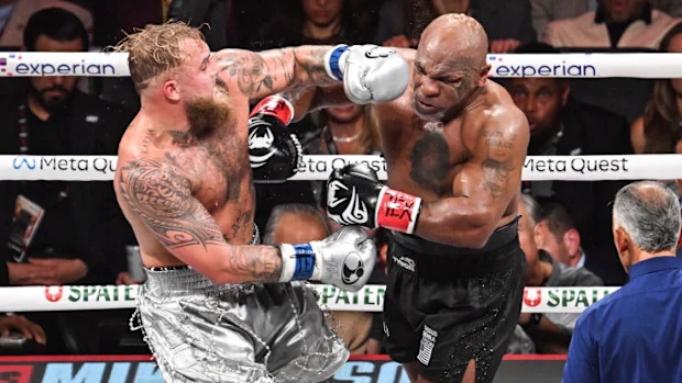 Mike Tyson (in black short) and Jake Paul (in silver short) exchange punches.
